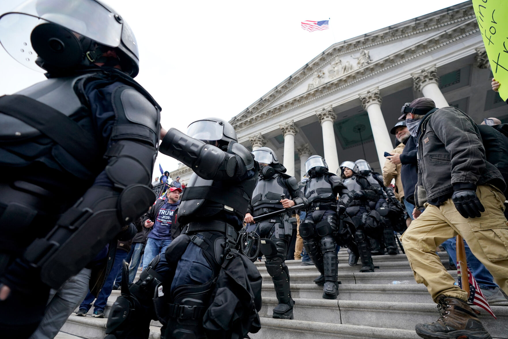 Police in riot gear walk out of the Capitol